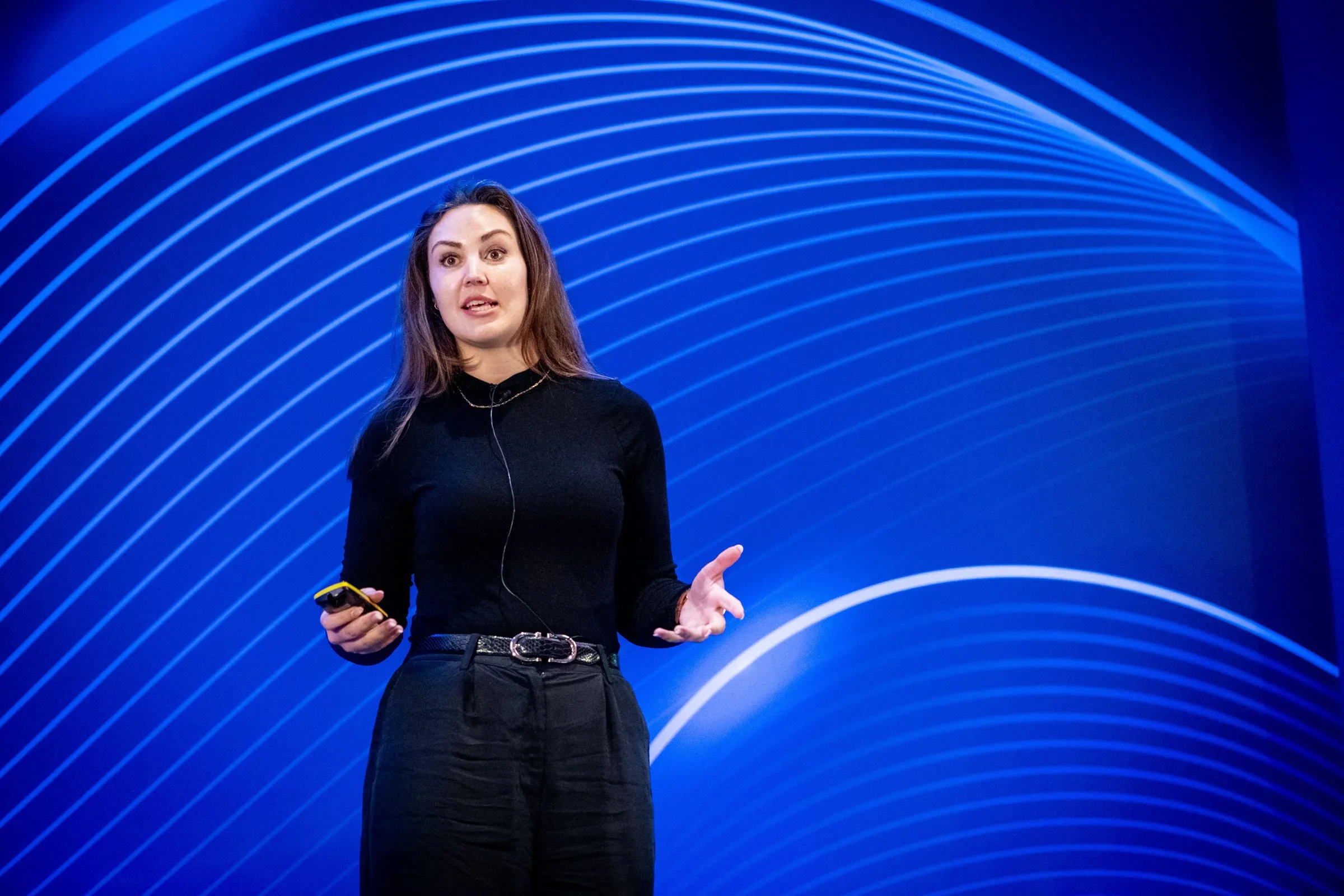 Eryn Peters speaking against a blue striped stage backdrop