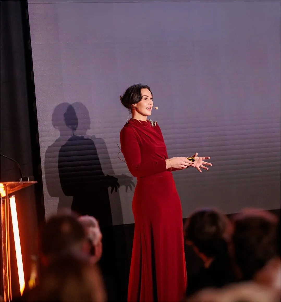 Eryn Peters in a red dress delivering the keynote at the Talent Business Awards